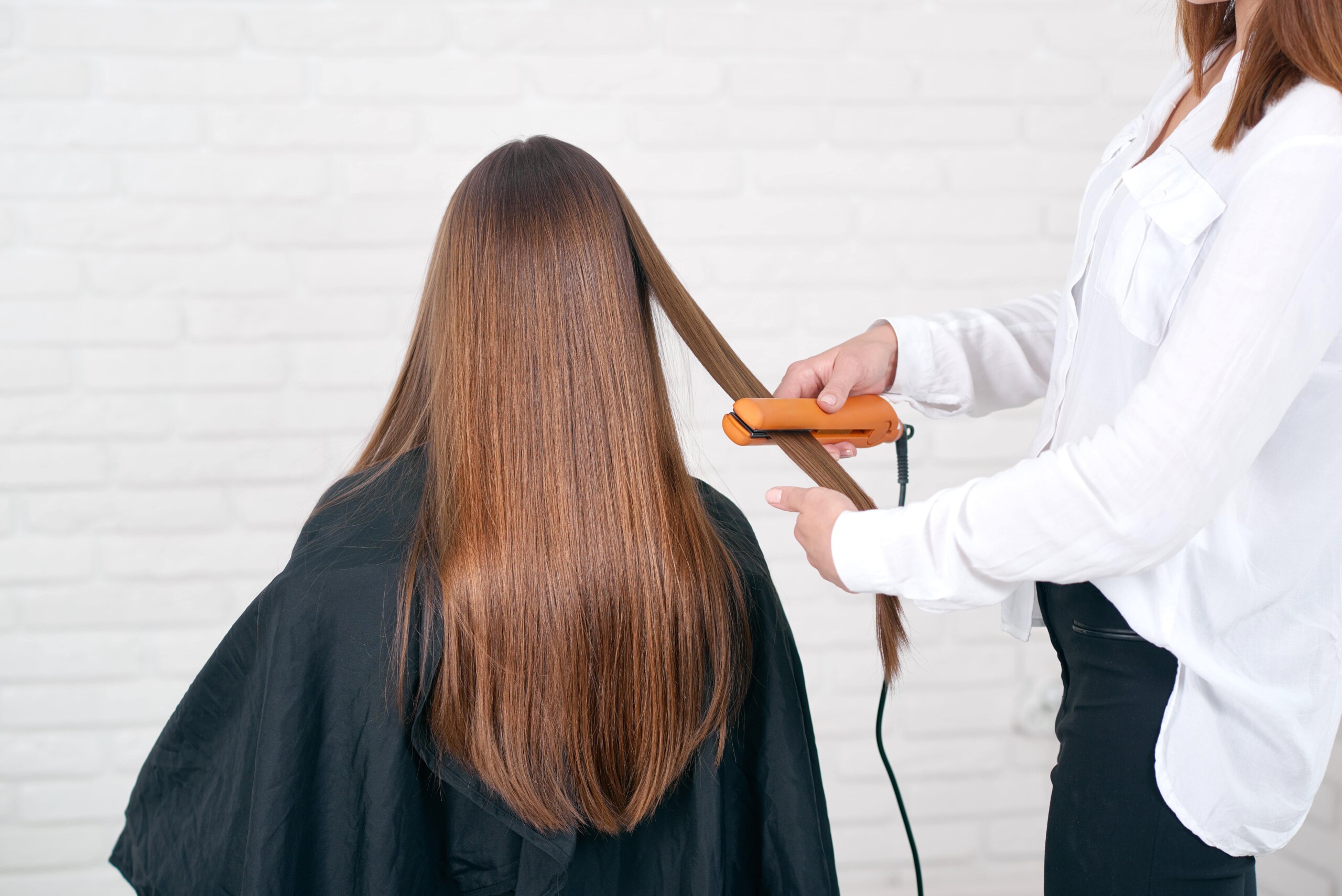 Stylist straightening hair during a Brazilian Blowout guide